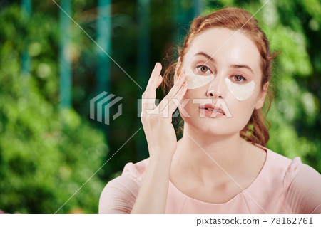 Woman applying undereye patches Woman applying undereye patches 78162761