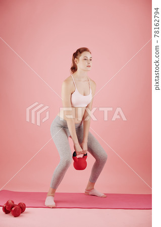 Woman doing deep squats with kettlebell Woman doing deep squats with kettlebell 78162794