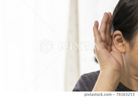 Close-up of a senior woman trying to listen with her hand on her ear (60s, Japanese) 78163253