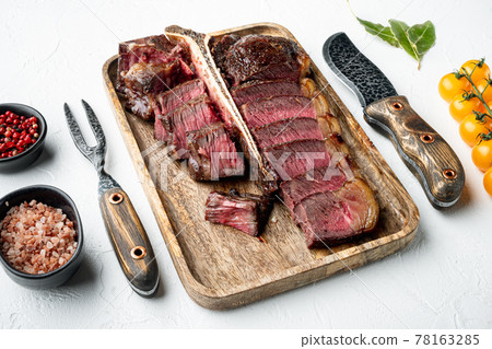 Grilled sliced t bone steak, on white stone background Grilled sliced t bone steak, on white stone background 78163285