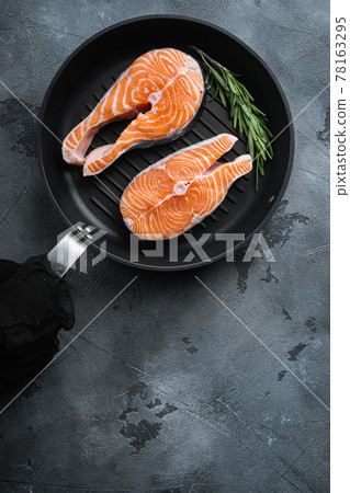 Slice of red fish salmon on grill skillet, over grey background, flat view with space for text Slice of red fish salmon on grill skillet, over grey background, flat view with space for text 78163295