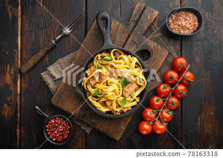 Homemade Rabbit stew pappardelle, in frying cast iron pan or pot, on old dark wooden table , top view flat lay Homemade Rabbit stew pappardelle, in frying cast iron pan or pot, on old dark wooden table , top view flat lay 78163318