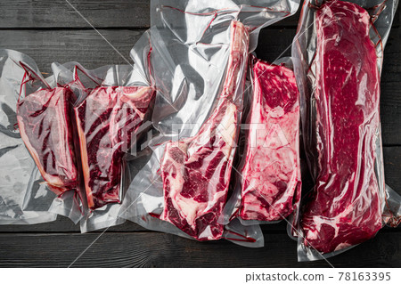 Plastic Market pack with fresh beef steak, tomahawk, t bone, club steak, rib eye and tenderloin cuts, on black wooden table background, top view flat lay Plastic Market pack with fresh beef steak, tomahawk, t bone, club steak, rib eye and tenderloin cuts, on black wooden table background, top view flat lay 78163395