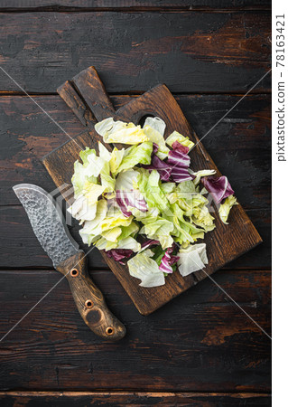 Organic Spring Mix Lettuce, on wooden cutting board, on old dark wooden table , top view flat lay Organic Spring Mix Lettuce, on wooden cutting board, on old dark wooden table , top view flat lay 78163421