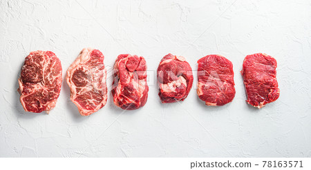 A set of different types of raw beef steaks:top blade, rump, chuck eye roll over white concrete background top view big size banner. A set of different types of raw beef steaks:top blade, rump, chuck eye roll over white concrete background top view big size banner. 78163571