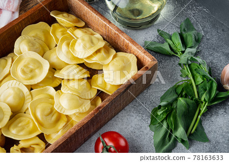 Italian raw handmade Ravioli with fresh ingredients, basil, pesto, ham, mozzarella cheese, parmesan, in wooden box, on gray background 78163633