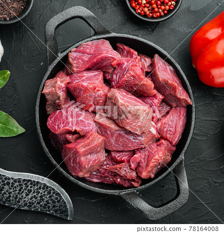 Beef stew raw ingredients, in cast iron frying pan, on black stone background, top view flat lay Beef stew raw ingredients, in cast iron frying pan, on black stone background, top view flat lay 78164008