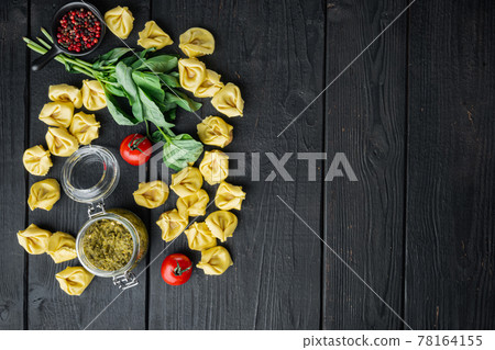 Raw Tortellini with basil and pine pesto, on black wooden table background, top view flat lay, with copy space for text Raw Tortellini with basil and pine pesto, on black wooden table background, top view flat lay, with copy space for text 78164155