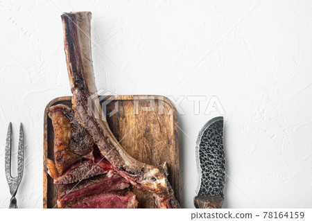 Medium rare Tomahawk meat marbled dry aged beef grilled, on wooden serving board, on white stone background, top view flat lay, with copy space for text 78164159