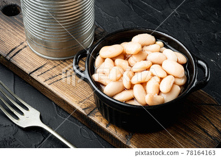 White canned beans, with metal can, in bowl, on black stone background White canned beans, with metal can, in bowl, on black stone background 78164163
