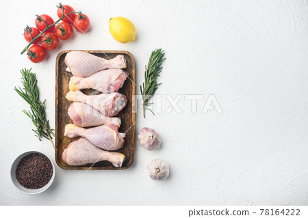Raw chicken drumsticks , with rosemary, spices and vegetables, on white background, top view flat lay, with copy space for text Raw chicken drumsticks , with rosemary, spices and vegetables, on white background, top view flat lay, with copy space for text 78164222