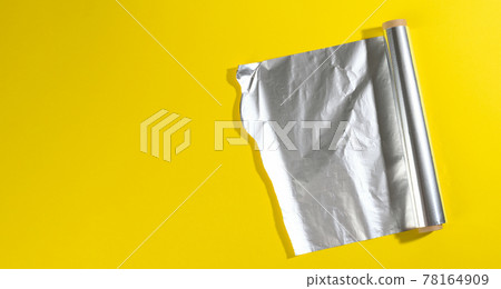 roll of twisted food foil for packaging food on yellow background roll of twisted food foil for packaging food on yellow background 78164909
