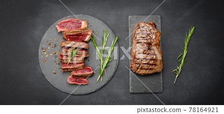 fried beef steaks cut into pieces on a black board, the degree of doneness rare with blood, top view 78164921