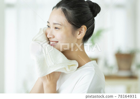 一位年輕的女士用毛巾擦臉 78164931