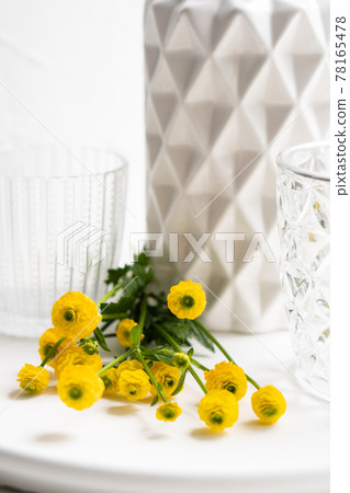 White home decoration with yellow flowers, ceramic vase and glass on tray White home decoration with yellow flowers, ceramic vase and glass on tray 78165478