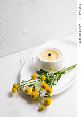 White burning candle with wooden wick and yellow flowers on white tray White burning candle with wooden wick and yellow flowers on white tray 78165505