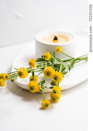 White burning candle with wooden wick and yellow flowers on white tray White burning candle with wooden wick and yellow flowers on white tray 78165506