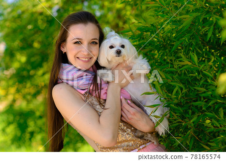 Young girl with her dog. Puppy white dog is running with it's owner. Concept about friendship, animal and freedom. 78165574