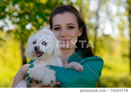 Young woman with her dog. Puppy white dog is running with it's owner. Concept about friendship, animal and freedom. Young woman with her dog. Puppy white dog is running with it's owner. Concept about friendship, animal and freedom. 78165579