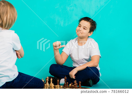 Two serious boy playing chess, studio, blue background Two serious boy playing chess, studio, blue background 78166012