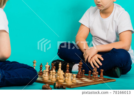 Two serious boy playing chess, studio, blue background Two serious boy playing chess, studio, blue background 78166013