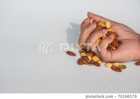 Concept, trail mix day. handful men trail mix on white background. closeup. copy space on left for design or text. 78166579