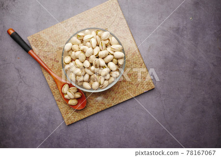 pistachios nut on in bowl and wooden spoon on black background pistachios nut on in bowl and wooden spoon on black background 78167067