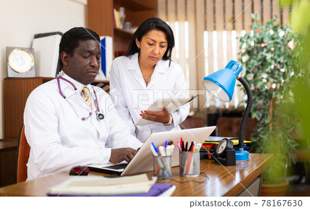 African american doctor working on laptop with female assistant 78167630