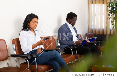 Adult hispanic woman using smartphone before interview with employer 78167653