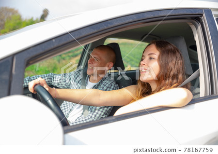 Attractive young woman and man talking and smiling in car Attractive young woman and man talking and smiling in car 78167759