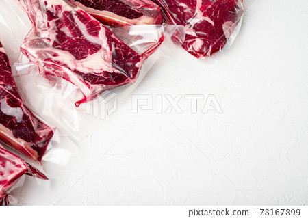 Fresh tasty raw beef steaks with bone wrapped in vacuum plastic packing at market, tomahawk, t bone, club steak, rib eye and tenderloin cuts, on white stone background, with copy space for text Fresh tasty raw beef steaks with bone wrapped in vacuum plastic packing at market, tomahawk, t bone, club steak, rib eye and tenderloin cuts, on white stone background, with copy space for text 78167899
