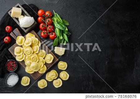 Homemade Ravioli with mozzarella cheese and basil, on wooden cutting board, on black background, top view flat lay, with copy space for text Homemade Ravioli with mozzarella cheese and basil, on wooden cutting board, on black background, top view flat lay, with copy space for text 78168076