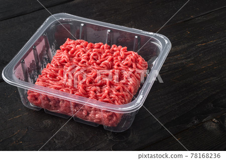 Raw Minced Meat in a transparent Plastic Container, on black wooden table , with copy space for text 78168236