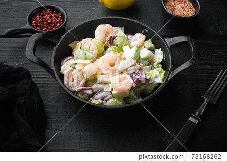 Salad with shrimp, avocado, tomatoes and mayonnaise on the lettuce , with sauce apple and grape, on black wooden table 78168262