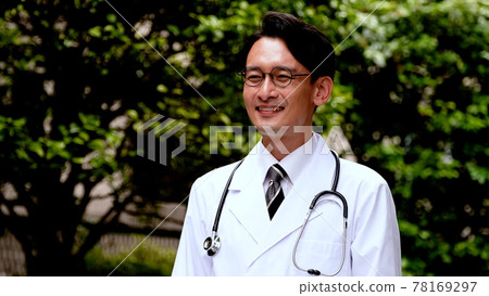 一位身穿白大褂的男醫生微笑著站著 一位身穿白大褂的男醫生微笑著站著 78169297