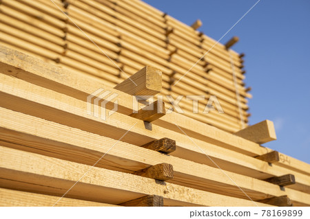 Storage of piles of wooden boards on the sawmill. Boards are stacked in a carpentry shop. Sawing drying and marketing of wood. Pine lumber for furniture production, construction. Lumber Industry. 78169899