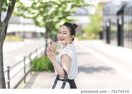 Woman holding a smartphone outdoors 78170419