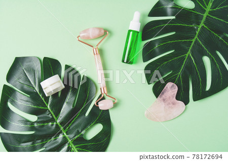 Roller and gua sha massage scraper and cometic product on a green background Roller and gua sha massage scraper and cometic product on a green background 78172694