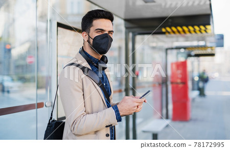 Young business man commuter with smartphone on the way to work outdoors in city, coronavirus concept. 78172995