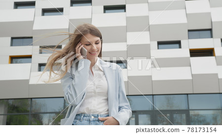 Caucasian Confident Young Business Woman in White Shirt is Talking on Phone Outside near Modern Office Building. Medium Long Low Angle 4K Slow Motion Corporate Shot with Moving Around. Career people Caucasian Confident Young Business Woman in White Shirt is Talking on Phone Outside near Modern Office Building. Medium Long Low Angle 4K Slow Motion Corporate Shot with Moving Around. Career people 78173154