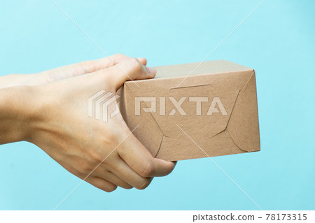 Woman hand hold the brown corrugated box on blue wall background with copy space Woman hand hold the brown corrugated box on blue wall background with copy space 78173315