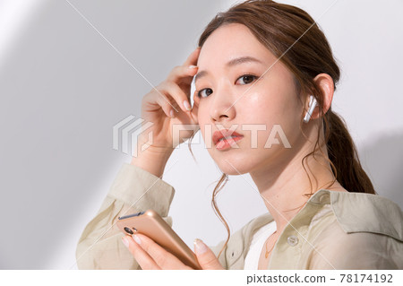 年輕女子在智能手機上聽她最喜歡的音樂 78174192