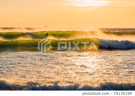 Surfing in ocean at waves. Surfer on sea wave with warm tones of sunset. Surfing in ocean at waves. Surfer on sea wave with warm tones of sunset. 78176199