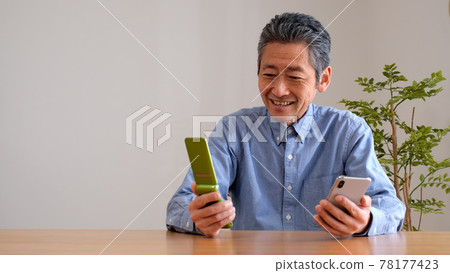 Senior man comparing a smartphone and a feature phone Senior man comparing a smartphone and a feature phone 78177423