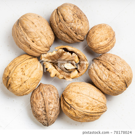 several shelled and whole walnuts close up on gray 78178024