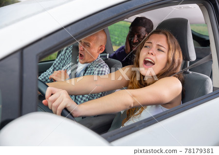 Frightened girl driving car with scared male passengers 78179381