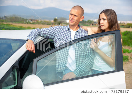 Positive young couple talking near car on spring day Positive young couple talking near car on spring day 78179387