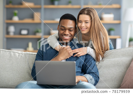 Portrait Of Happy Happy Young Multicultural Spouses Using Laptop At Home Portrait Of Happy Happy Young Multicultural Spouses Using Laptop At Home 78179939
