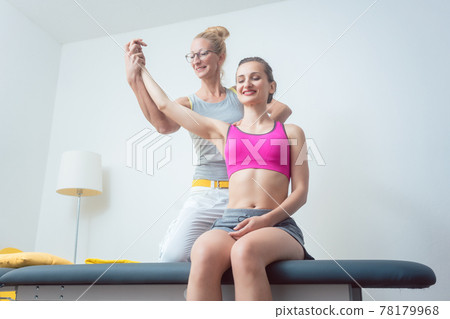 Physical therapist mobilizing arm of woman 78179968