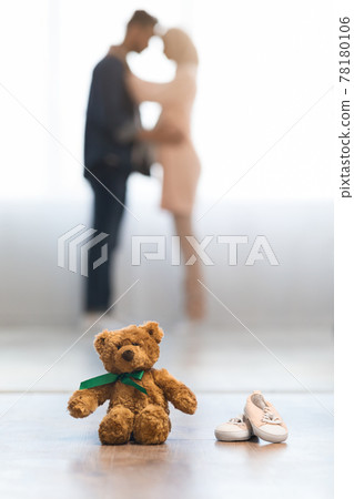 Teddy Bear And Small Baby Shoes With Blurred Pregnant Couple On Background Teddy Bear And Small Baby Shoes With Blurred Pregnant Couple On Background 78180106